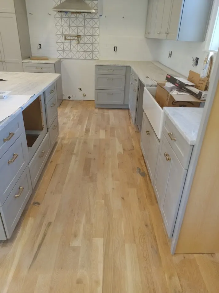 Finished white oak flooring in a renovated kitchen with grey cabinets