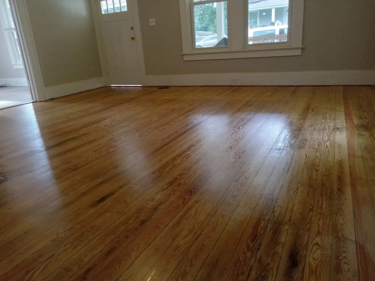 After: seventy-year-old heart pine floor refinished by AMAX Flooring, glowing amber in a sunlit room