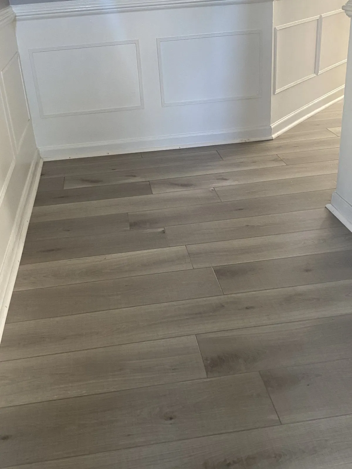 Grey plank flooring along white wainscoting